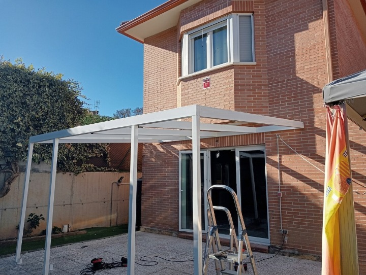 Pérgola metálica blanca instalada en jardín de vivienda unifamiliar por CB Estructuras